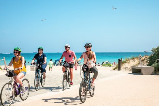 4 pessoas pedalando bikes de aluguel numa bela paisagem