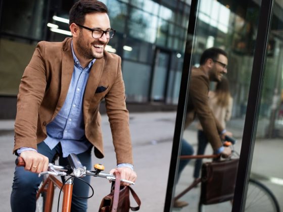 Feliz jovem elegante indo trabalhar de bike compartilhada