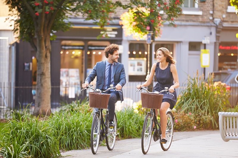 Homem e mulher de negócios se deslocando de bicicleta pela cidade.